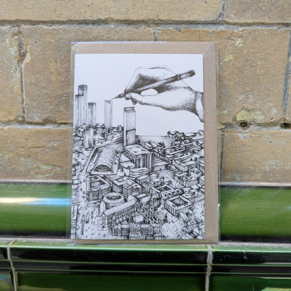 Greeting card with a hand-drawn cityscape and pen on a brick background